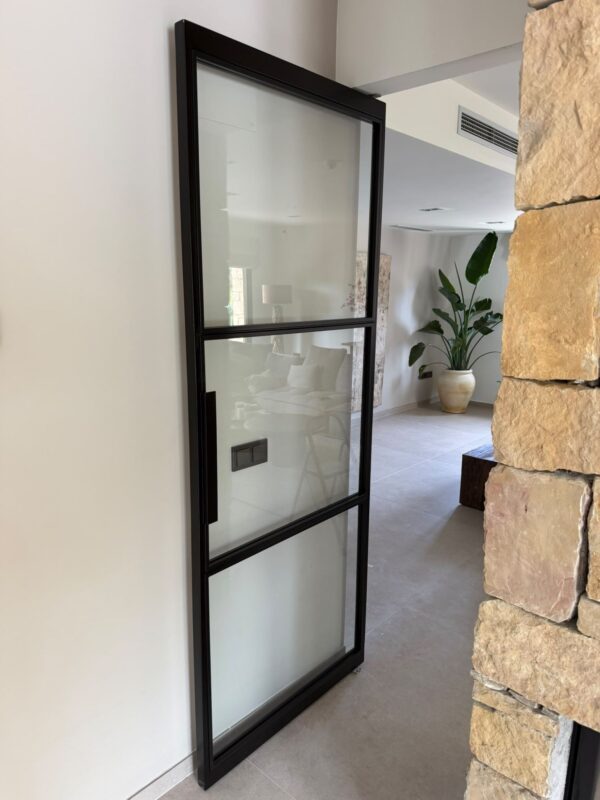 Puerta pivotante de acero negro con tres paneles de cristal y tirador